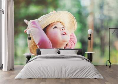 Happy little girl playing outside in a hat Wall mural