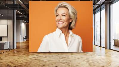 Happy mature businesswoman on an orange solid background Wall mural