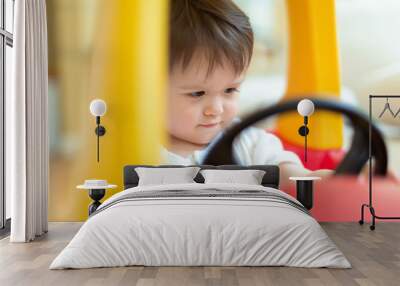 Happy toddler boy having fun playing in his toy car Wall mural