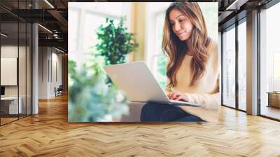 happy young latina woman using her laptop at home Wall mural