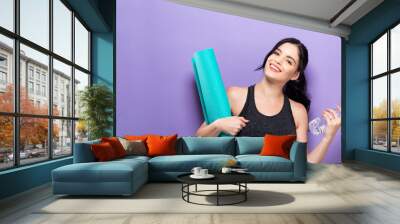 Happy young woman holding a yoga mat Wall mural