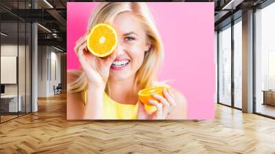 Happy young woman holding orange halves Wall mural