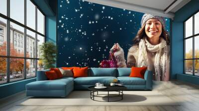 Happy young woman holding shopping bags in a snowy night Wall mural