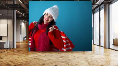 Happy young woman holding shopping bags on a dark blue background Wall mural