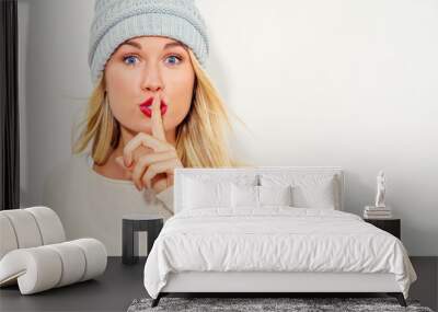 Happy young woman making a quiet gesture on a white background Wall mural