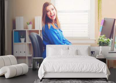 Happy young woman using a her computer Wall mural