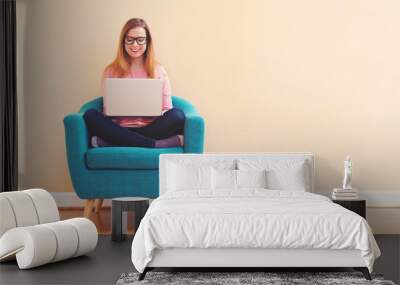 Happy young woman using her laptop computer at home Wall mural