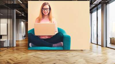 Happy young woman using her laptop computer at home Wall mural