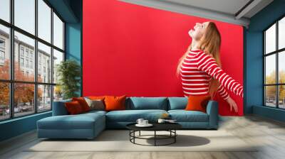 Happy young woman with her arms outstretched on a red background Wall mural