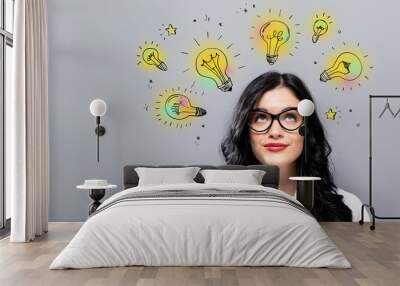 Idea light bulbs with young businesswoman in a thoughtful face Wall mural