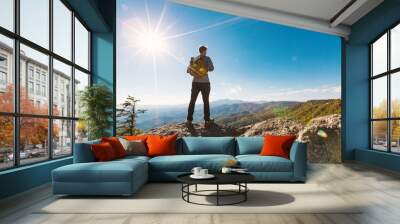 Man walking on the edge of a cliff high above the mountains Wall mural