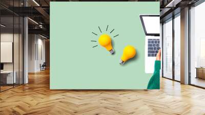 Person using a laptop computer and light bulbs - Flat lay Wall mural