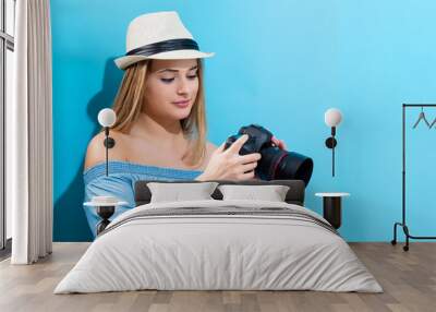 Young woman holding a camera on a blue background Wall mural