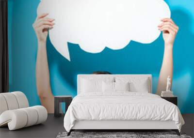 Young woman holding a speech bubble on a blue background Wall mural