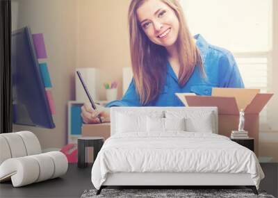 Young woman packing boxes to be shipped Wall mural