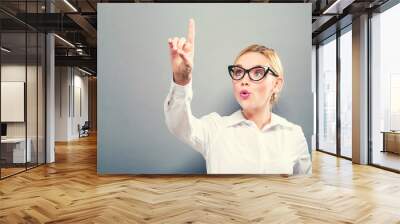 Young woman pointing at something on a solid background Wall mural