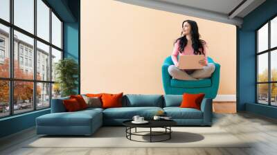 Young woman using her laptop on a blue chair Wall mural