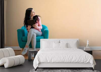 Young woman using her tablet on a blue chair Wall mural