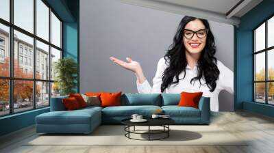 Young woman with a displaying hand gesture on a solid background Wall mural