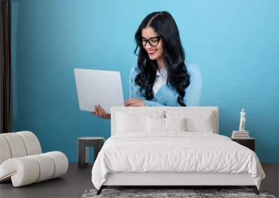 Young woman with a laptop computer on a blue background Wall mural