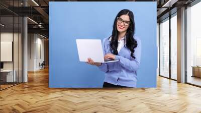 Young woman with a laptop computer on a blue background Wall mural