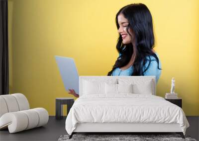 Young woman with a laptop computer on a yellow background Wall mural