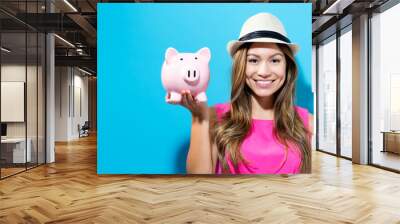 young woman with a piggy bank on a blue background Wall mural