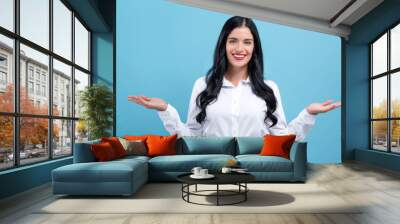 Young woman with her arms outstretched on a blue background Wall mural