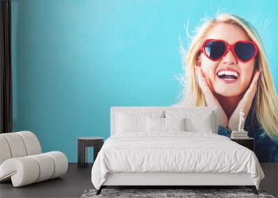 Young woman with sunglasses on a blue background Wall mural