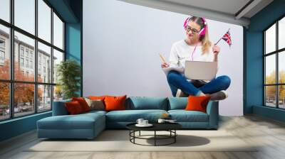 Young woman with UK flag using a laptop computer on a gray background Wall mural