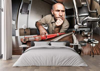  plumber  looks at the sink pipes not knowing how to solve the problem. concept of difficulty at work Wall mural