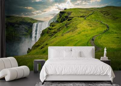 Tourists walking up path with waterfall and green grass in iceland Wall mural