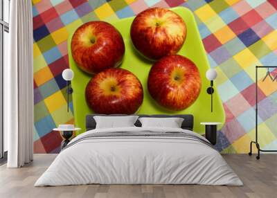 close up of four red fresh apples on a green plate on a colourful table cloth Wall mural