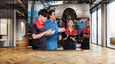 Specialist lecture. Male supervisor engineer describe automotive suspension fixing with mechanic worker staff teams for repair work at car service garage and maintenance jobs in automobile industry. Wall mural