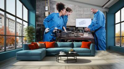 Three multiracial professional industry engineer workers teams in safety uniforms metalwork jobs discuss with mechanical drawing in a monitor, lathe machines, and workshop in manufacturing factory. Wall mural