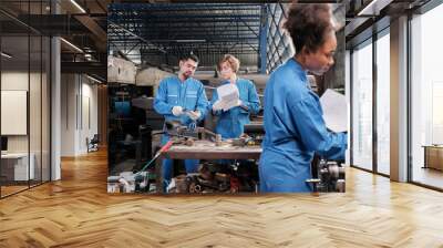 Two professional industry workers in safety uniforms and engineers' partners discussed mechanical drawing for lathe machines in manufacturing factory, with African American colleague in front of them. Wall mural