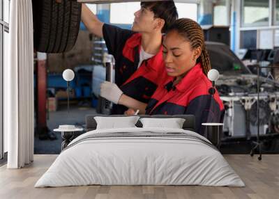 Young expert Black female inspects repair checklist with automotive mechanic worker partner, quality suspension technician team at fix garage. Vehicle maintenance service works industry occupation job Wall mural