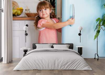 A little girl opens the door of the refrigerator. Beautiful kitchen. Wall mural