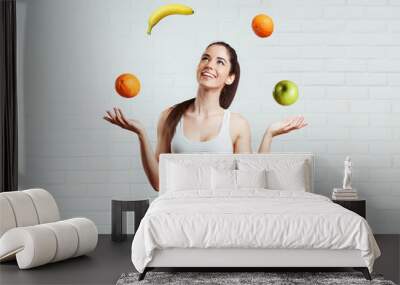 Beautiful, fit, young woman joggling with fruit, over a white brick wall Wall mural