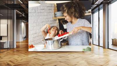 Beautiful African American woman and her daughter cooking in the kitchen  Wall mural