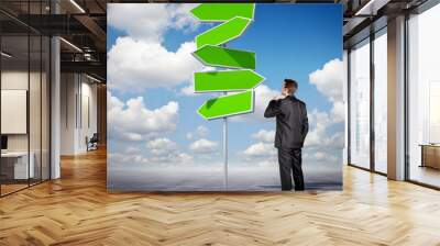 Businessman looking at an arrow sign Wall mural