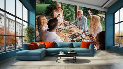 Family cheering over the dining table outdoors, celebration  Wall mural