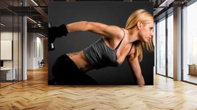 Fit woman exercising with weights over a dark background Wall mural