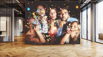 Group of people having a party, blowing confetti  Wall mural