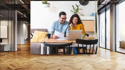 Happy husband and wife read good news online at laptop, smiling man holding documents receiving positive decision from bank Wall mural