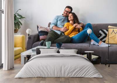 Loving couple embracing on sofa stock photo Wall mural