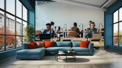 Mixed-Race Team  Sitting at Two Desk and Working in Open Plan Business Space Office.
Group of six multi-ethnic businesspeople working together in an open plan office on a laptop computers Wall mural