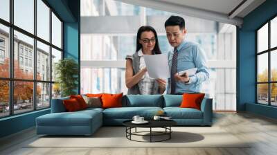 Two cheerful business people reading papers documents and using digital tablet together
Businesswoman showing good news on papers to handsome businessman who is holding white digital tablet Wall mural