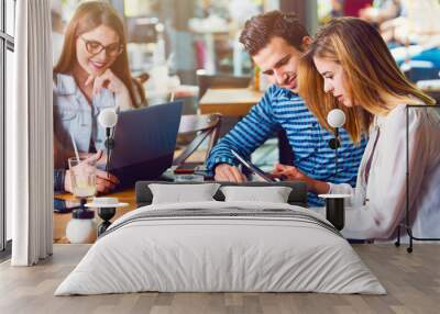 Two young people, man and woman, looking at a tablet Wall mural