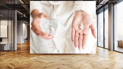 woman holding a glass of water and pills, detail Wall mural